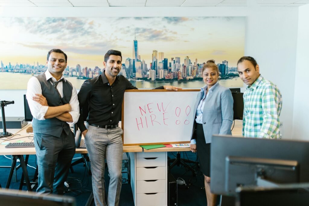 Diverse team standing with 'New Hire' sign, symbolizing collaboration and teamwork.